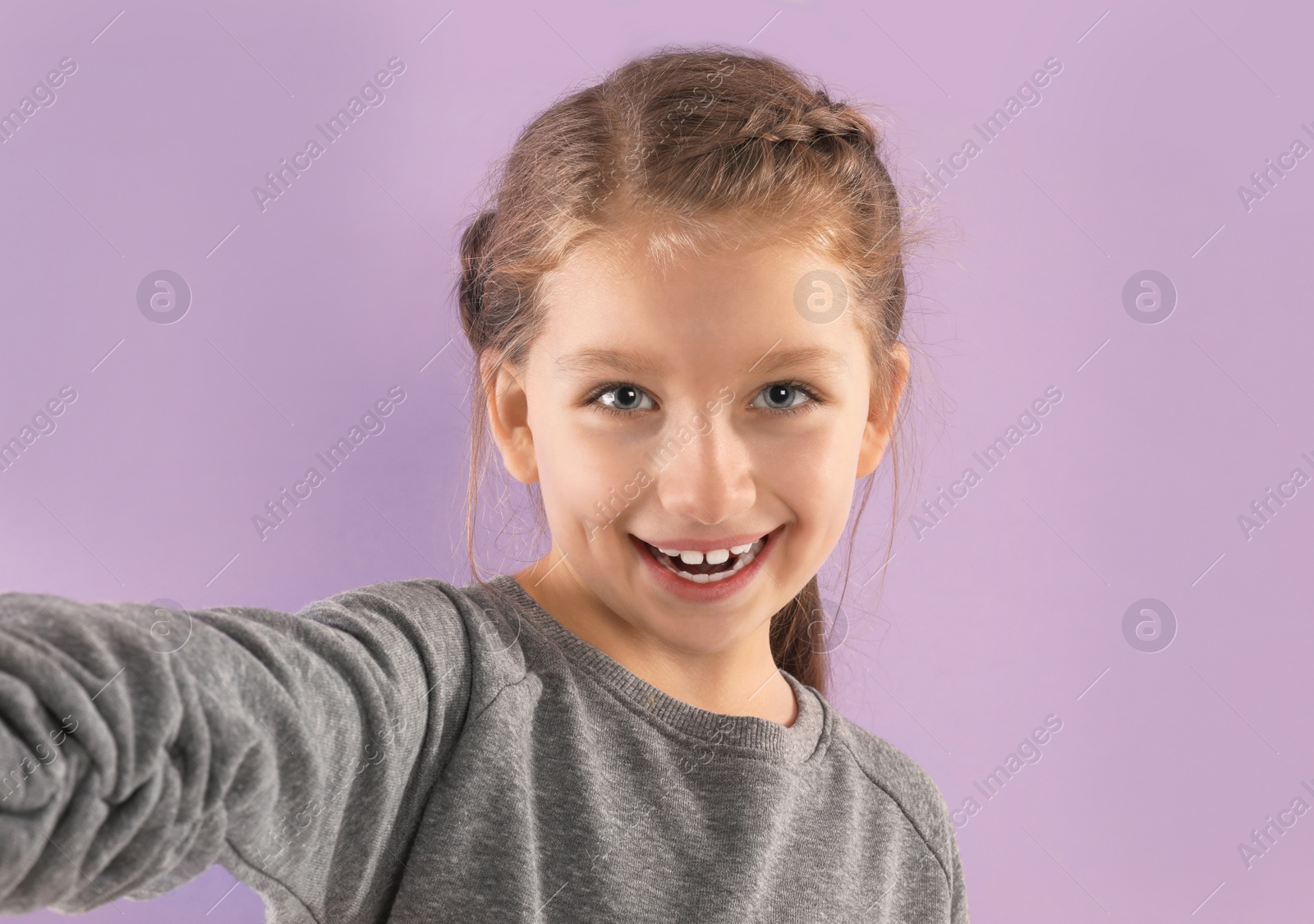 Photo of Cute little blogger recording video on violet background