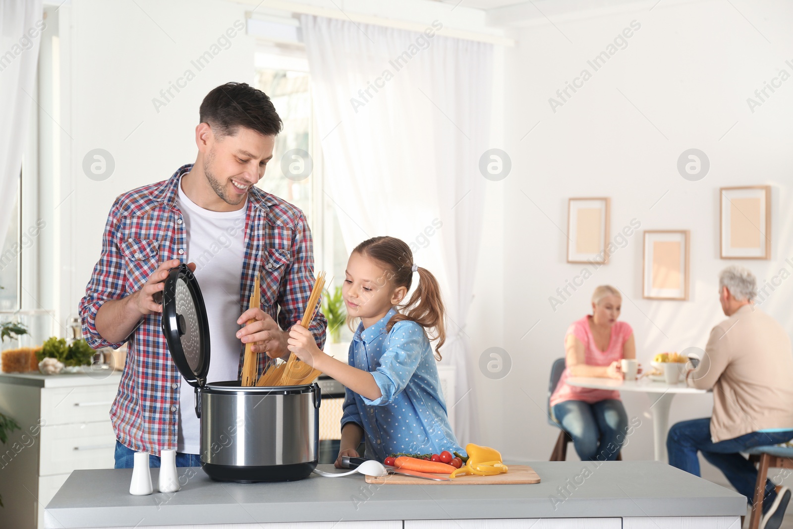 Photo of Father and daughter preparing food with modern multi cooker in kitchen