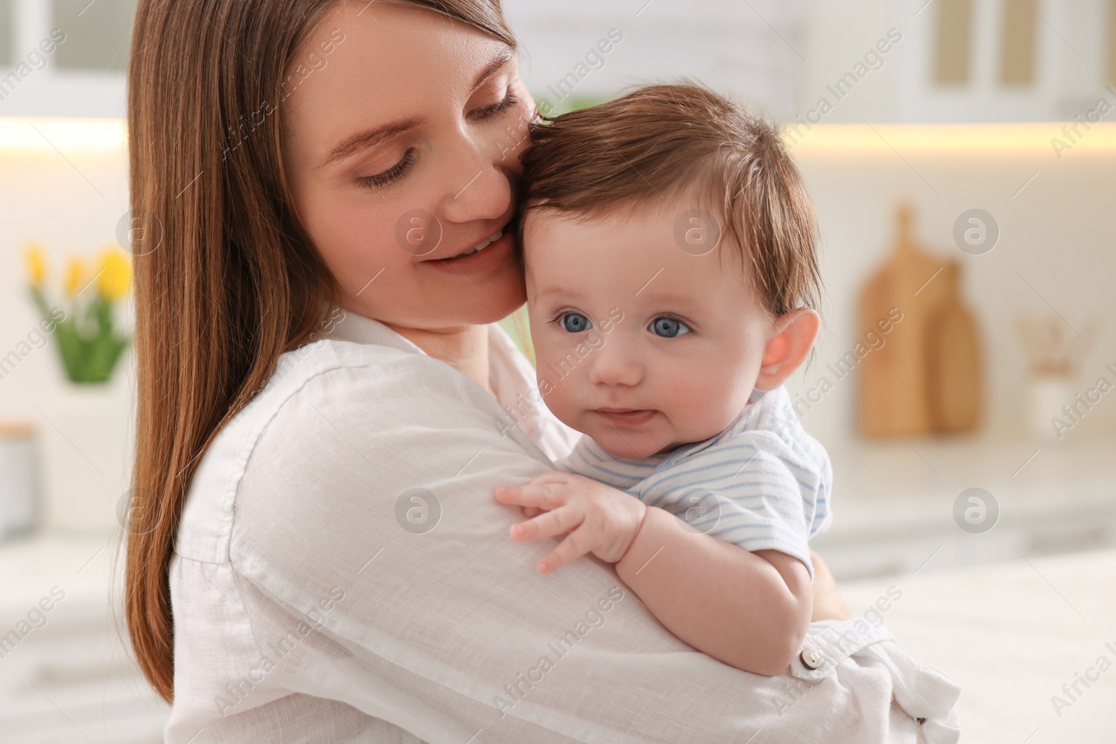 Photo of Happy mother with her little baby in kitchen, closeup