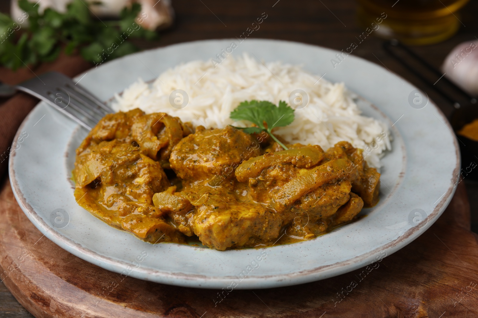 Photo of Delicious chicken curry with rice on wooden table, closeup