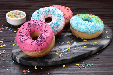 Photo of Sweet glazed donuts decorated with sprinkles on wooden table. Tasty confectionery