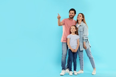 Happy family on light blue background, space for text