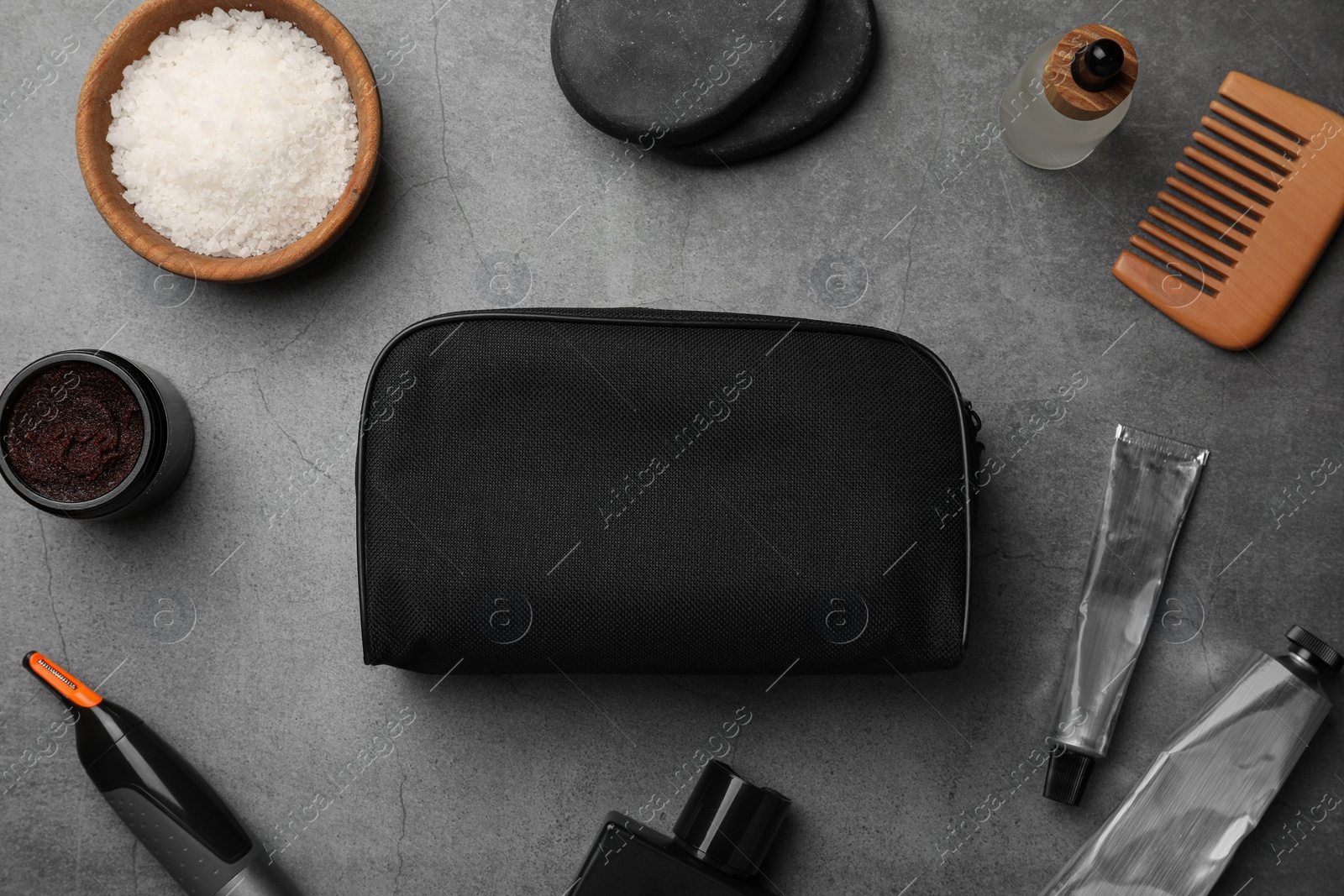 Photo of Compact toiletry bag, spa stones and different cosmetic products on grey textured background, flat lay