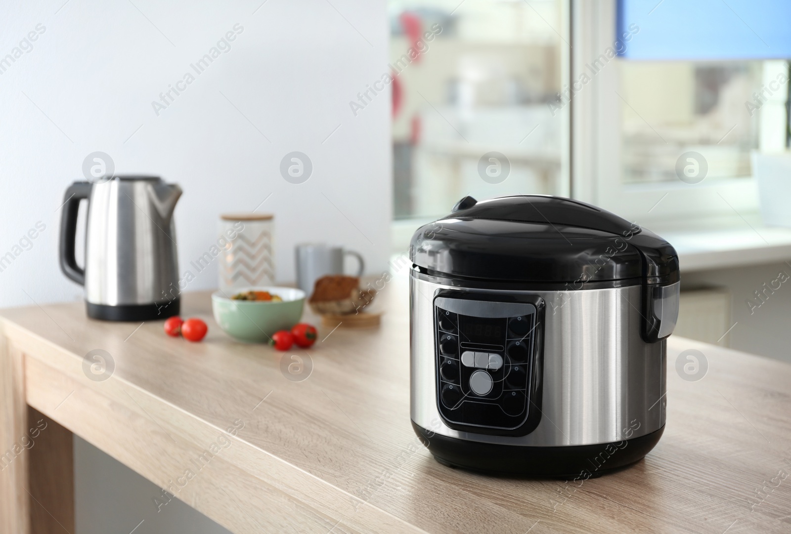 Photo of Modern multi cooker and ingredients on table in kitchen