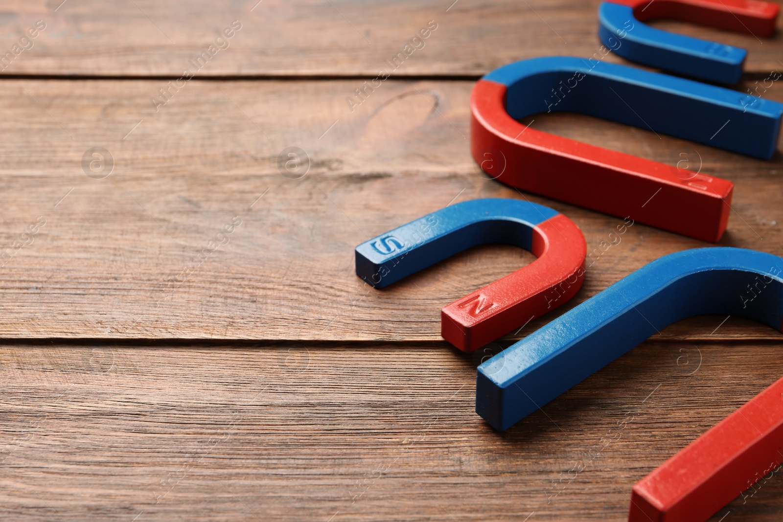 Photo of Red and blue horseshoe magnets on wooden background. Space for text