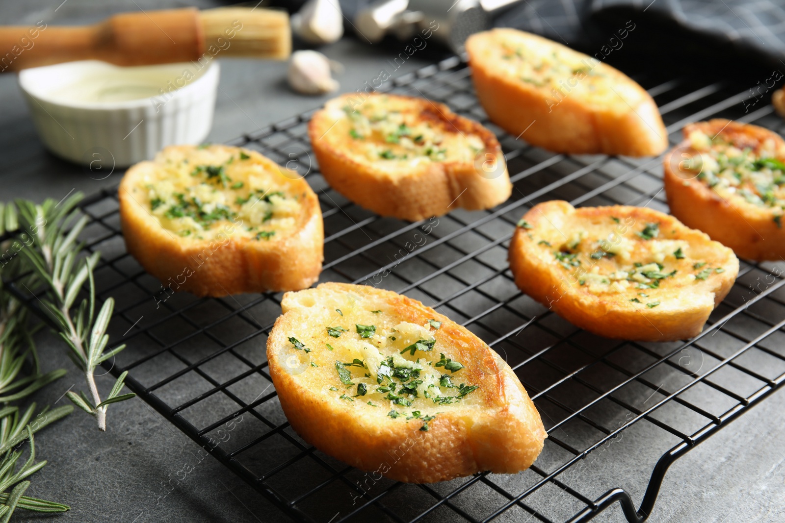 Photo of Baking rack with tasty homemade garlic bread on table