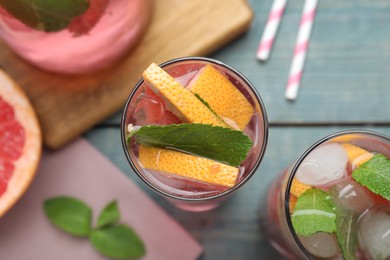 Photo of Delicious grapefruit lemonade with soda water and mint on blue wooden table, flat lay. Fresh summer cocktail