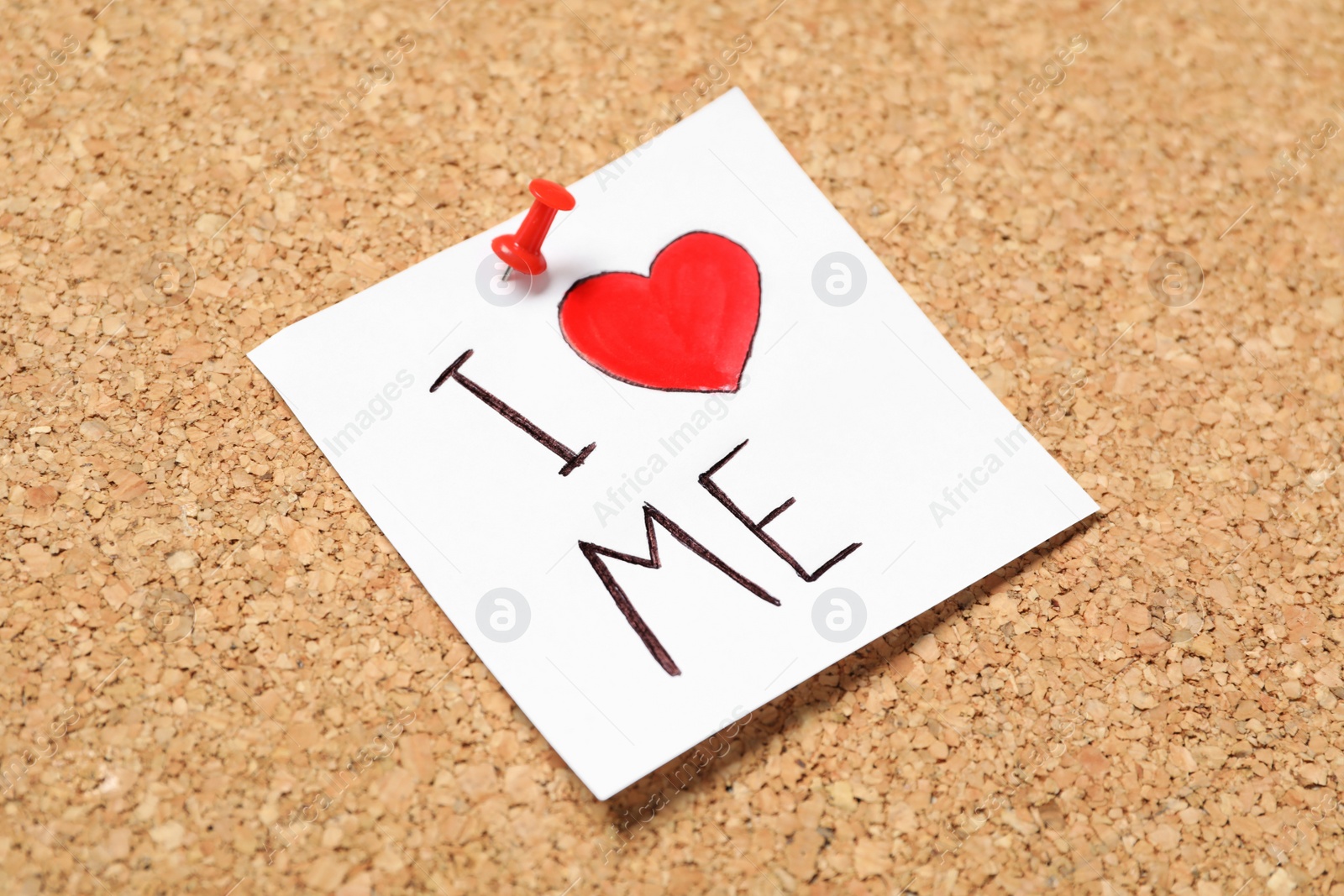 Photo of Paper note with phrase I Love Me pinned to cork board