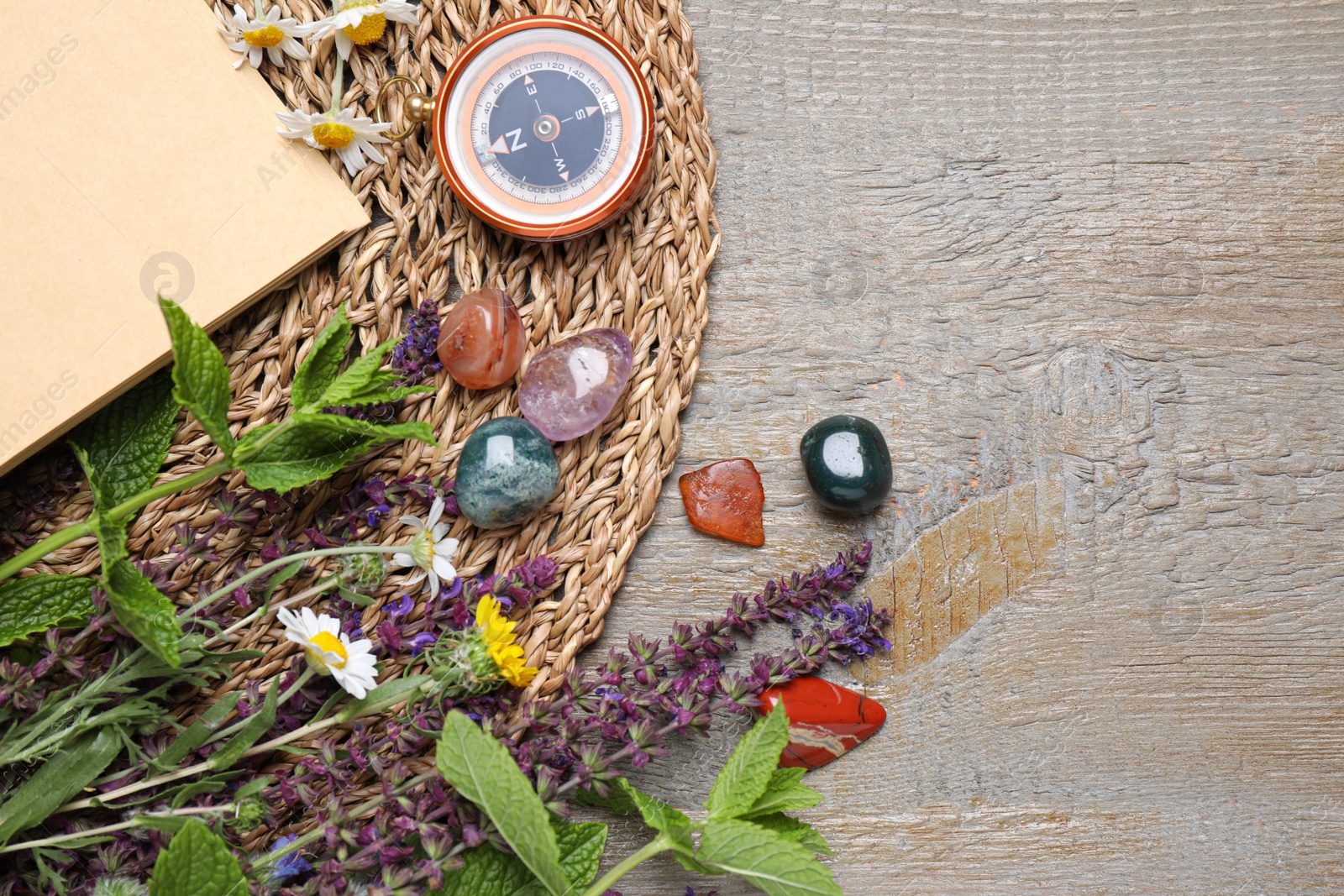 Photo of Flat lay composition with different gemstones and healing herbs on wooden table, space for text