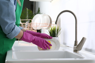 Woman washing plate in modern kitchen, closeup