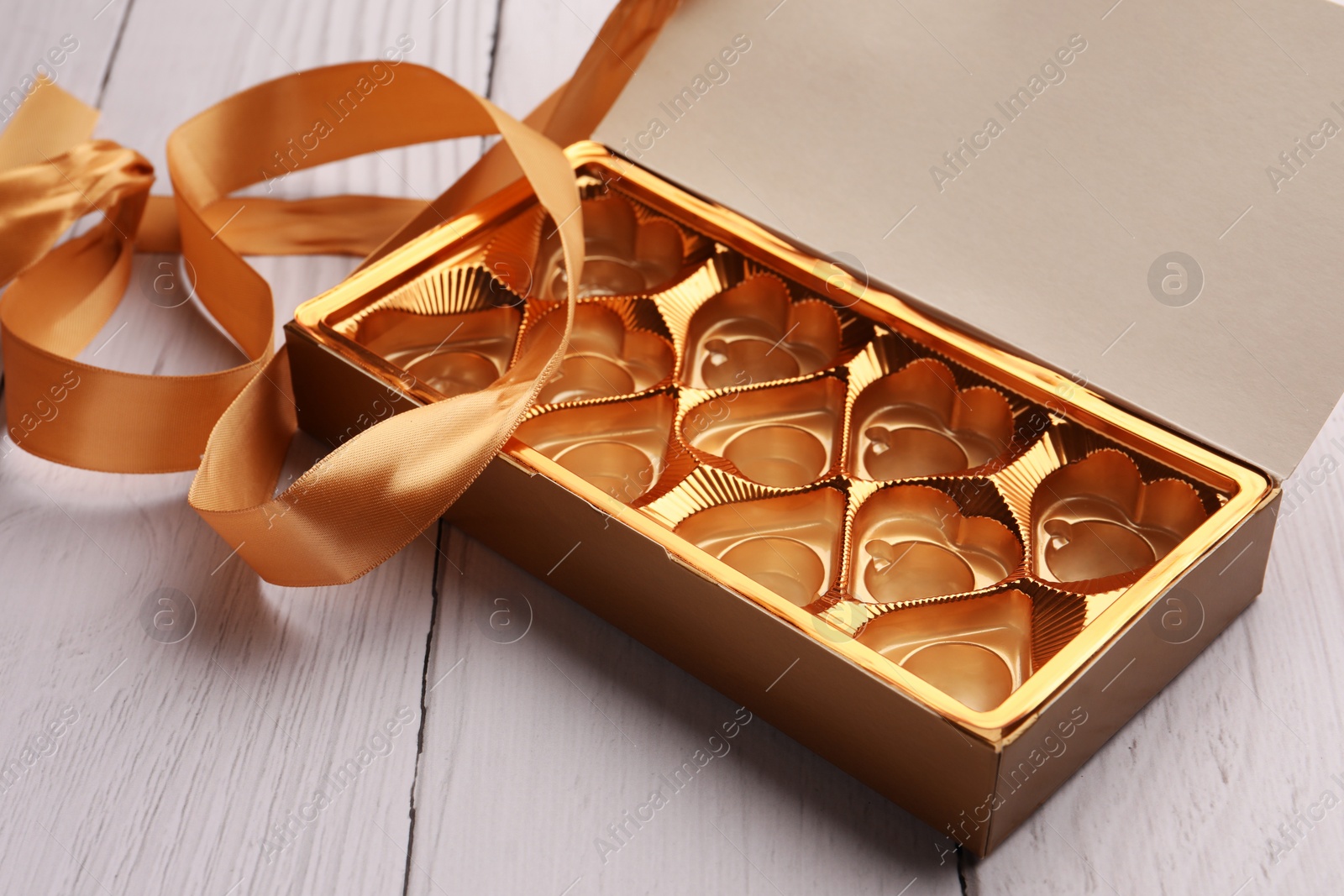 Photo of Empty box of chocolate candies on white wooden table