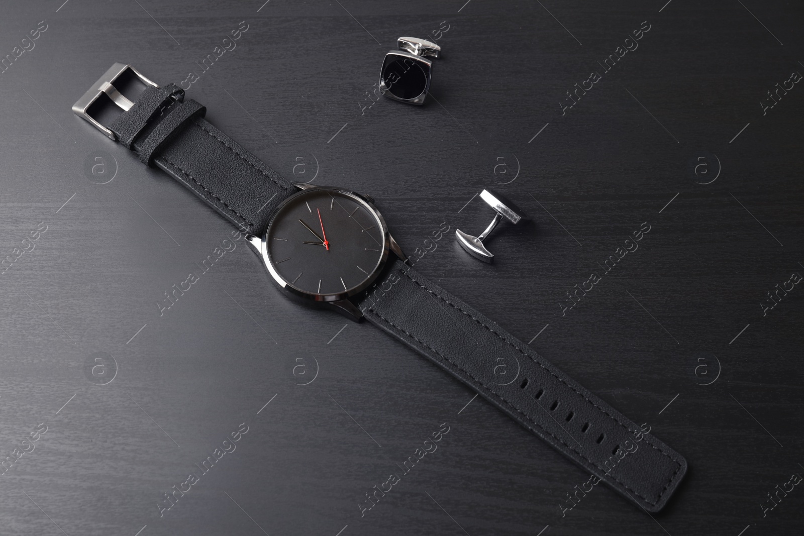 Photo of Stylish wrist watch and cuff links on dark table. Fashion accessory
