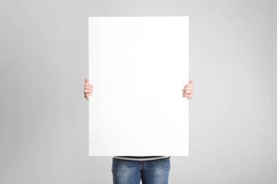 Photo of Man holding blank poster on light grey background