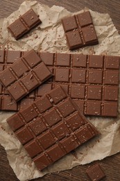 Photo of Pieces and crumbs of tasty chocolate bars on wooden table, flat lay