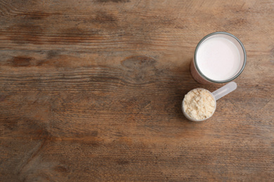 Photo of Protein shake and powder on wooden table, flat lay. Space for text