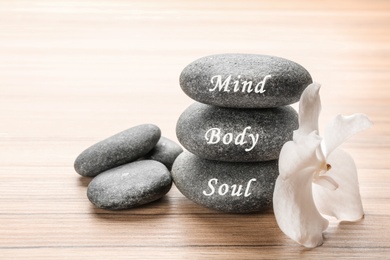 Image of Stones with words Mind, Body, Soul and orchid on wooden table. Zen lifestyle