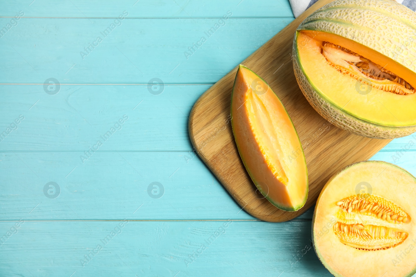 Photo of Tasty fresh melons on light blue wooden table, flat lay. Space for text