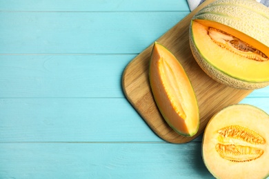 Tasty fresh melons on light blue wooden table, flat lay. Space for text