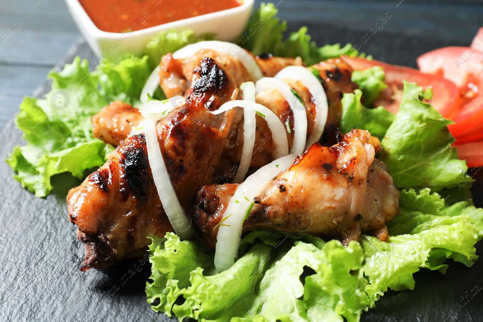 Photo of Tasty shish kebab served on slate plate, closeup