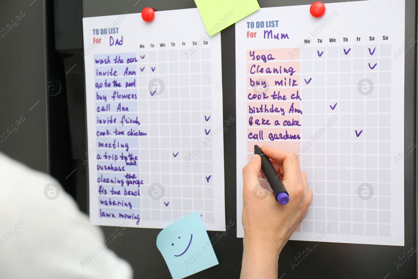 Photo of Woman writing to do list on refrigerator door in kitchen, closeup