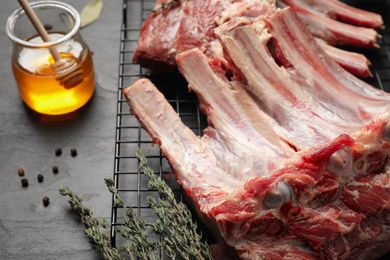 Photo of Raw ribs with thyme on black table, closeup