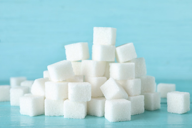 Heap of refined sugar cubes on blue wooden background