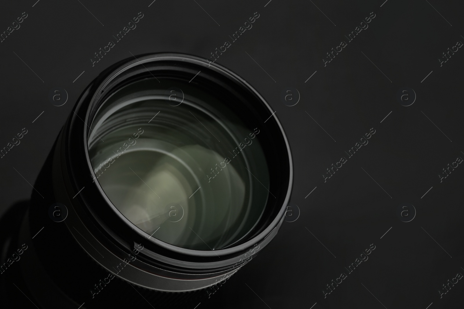 Photo of Modern camera lens on black background, closeup. Space for text