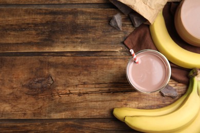 Photo of Yummy chocolate milk and fresh ingredients on wooden table, flat lay. Space for text