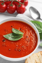 Photo of Delicious tomato cream soup in bowl served on table, closeup