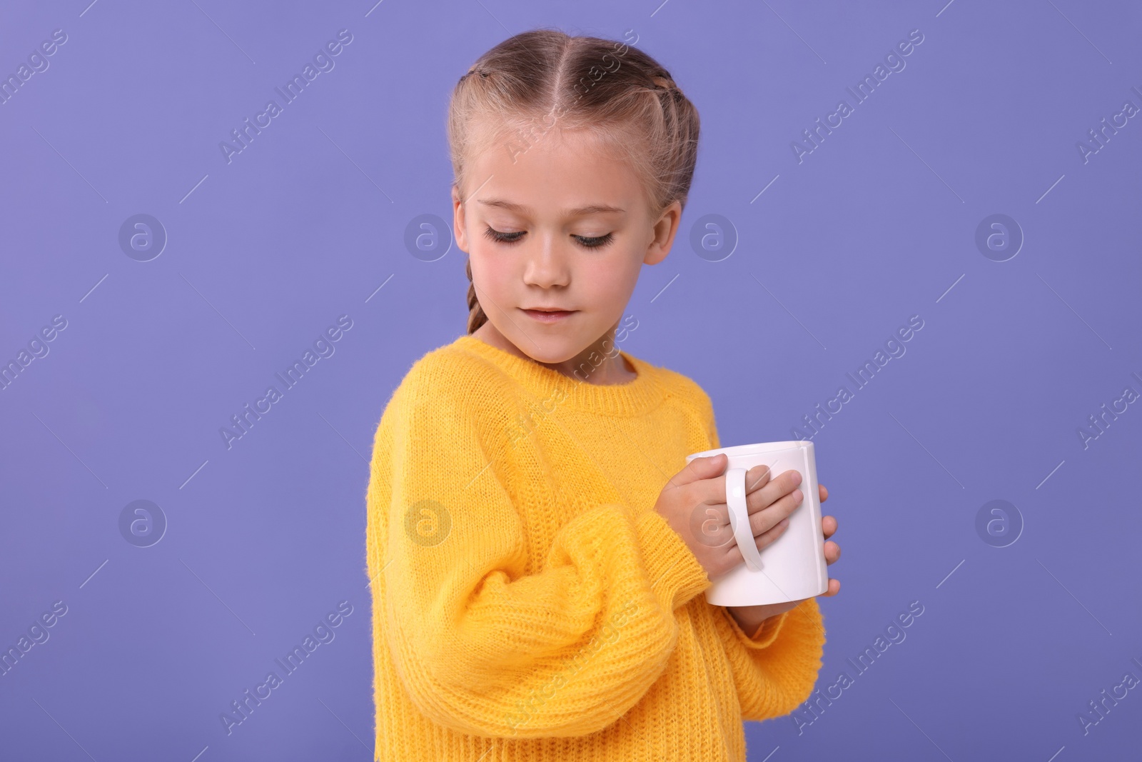 Photo of Cute girl with white ceramic mug on violet background