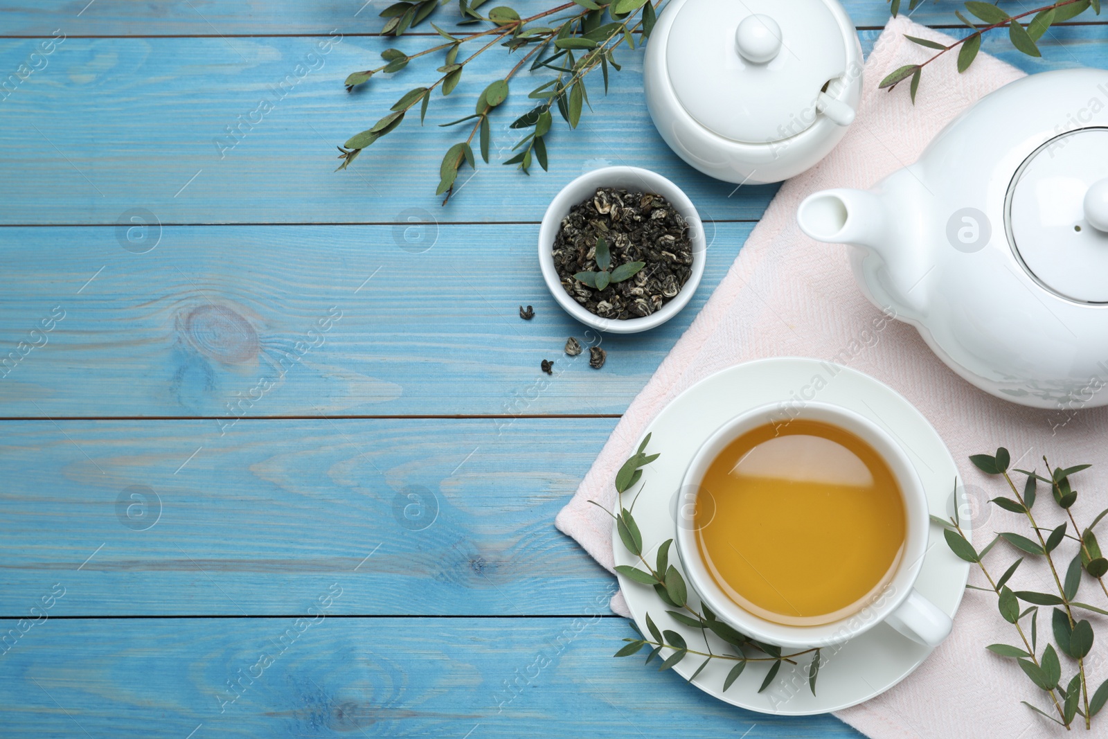 Photo of Aromatic eucalyptus tea on light blue wooden table, flat lay. Space for text