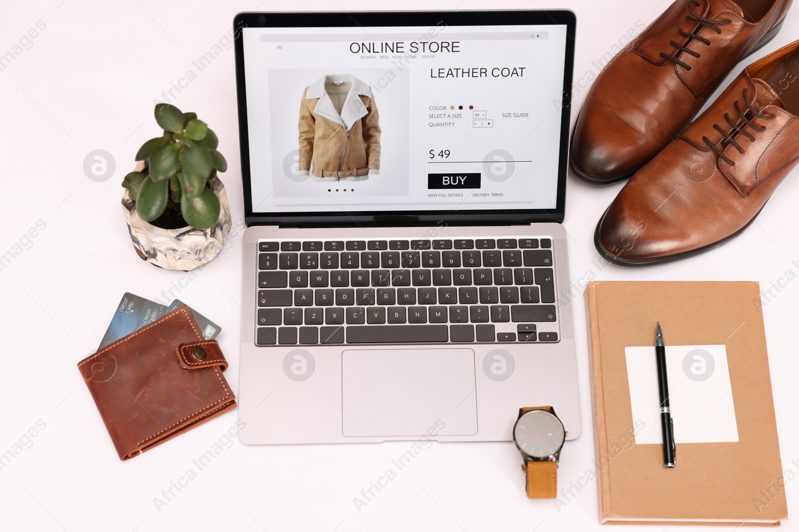 Photo of Online store website on laptop screen. Computer, stationery, credit cards, men's shoes and accessories on white background, above view