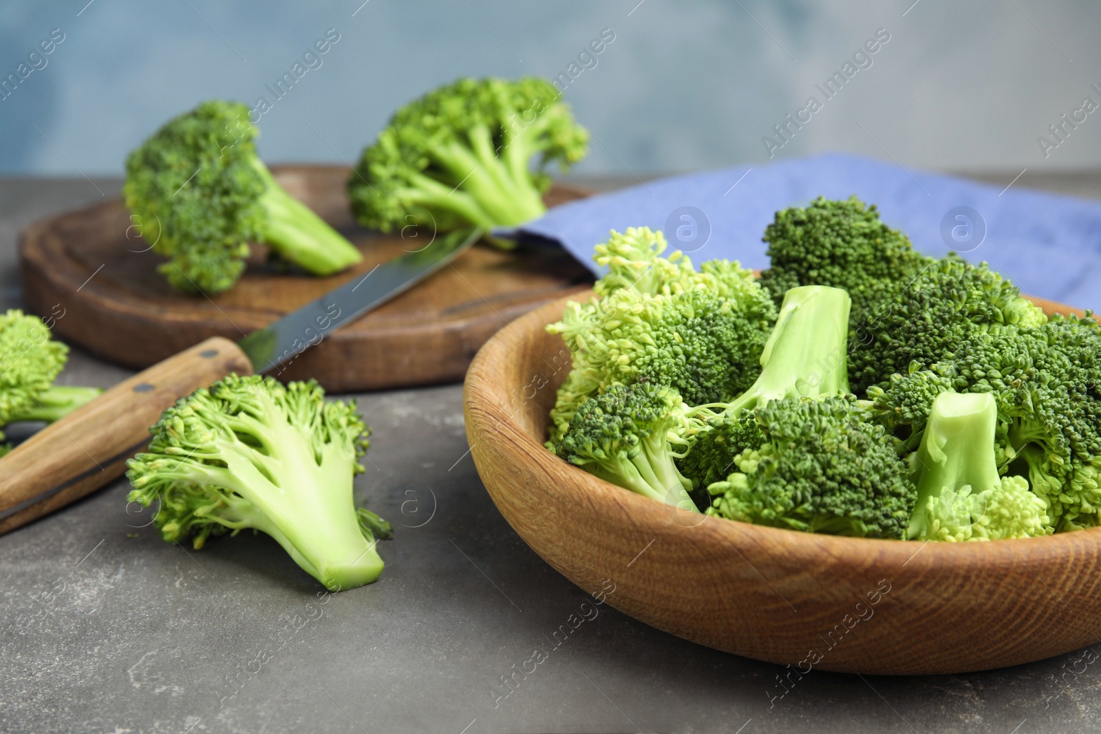 Photo of Fresh green broccoli in wooden bowl on grey table