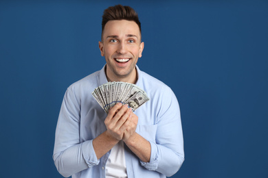 Photo of Emotional man with cash money on blue background