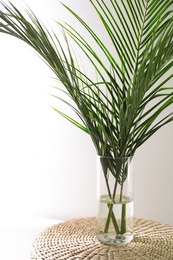 Photo of Green tropical leaves in vase on table. Modern decor for stylish interior