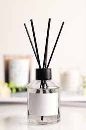 Photo of Aromatic reed air freshener on white table, closeup