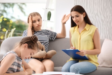 Photo of Young mother and her daughter visiting child psychologist in office