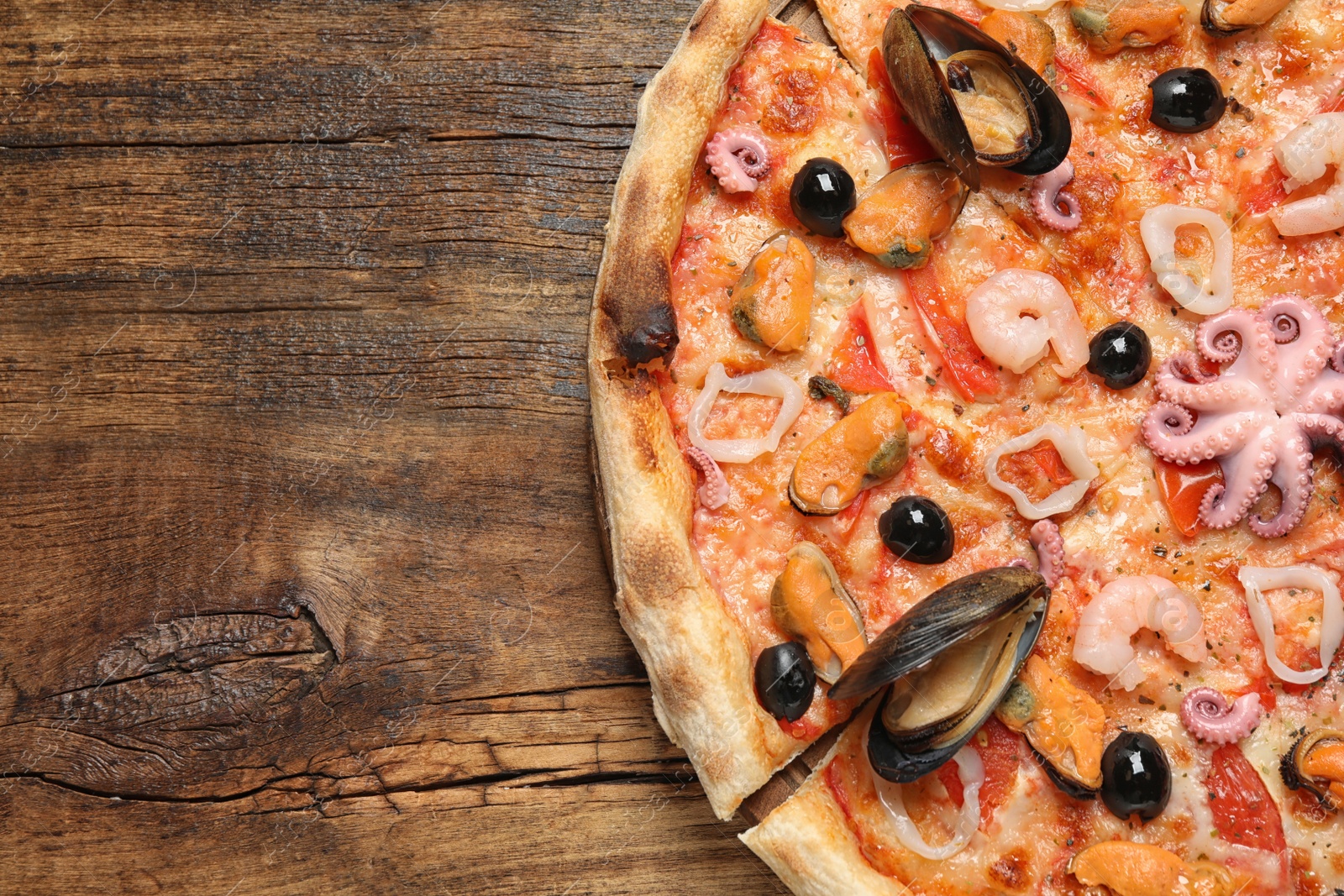 Photo of Delicious seafood pizza on wooden table, top view. Space for text