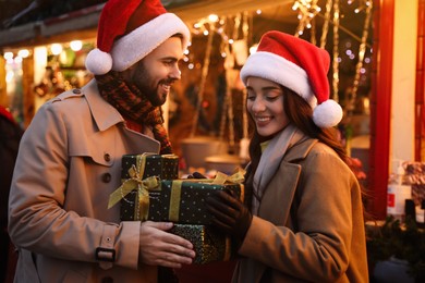 Photo of Lovely couple with Christmas presents at winter fair