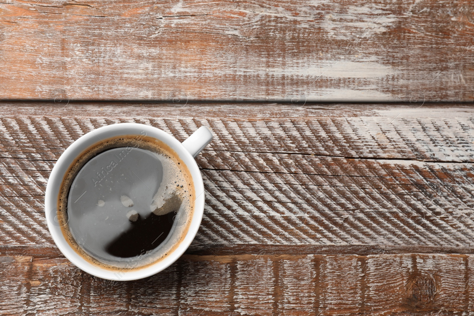 Photo of Cup of aromatic coffee on wooden table, top view. Space for text