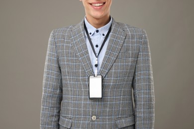 Man with blank badge on grey background, closeup