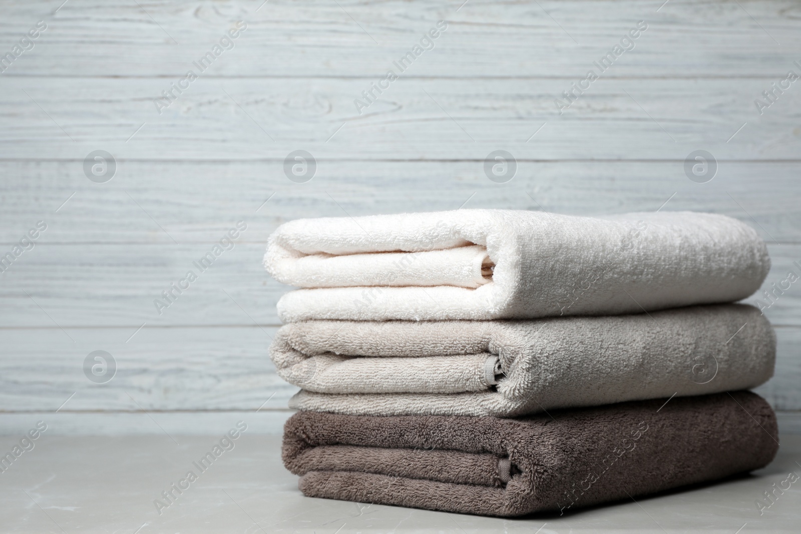 Photo of Stack of fresh towels on table. Space for text