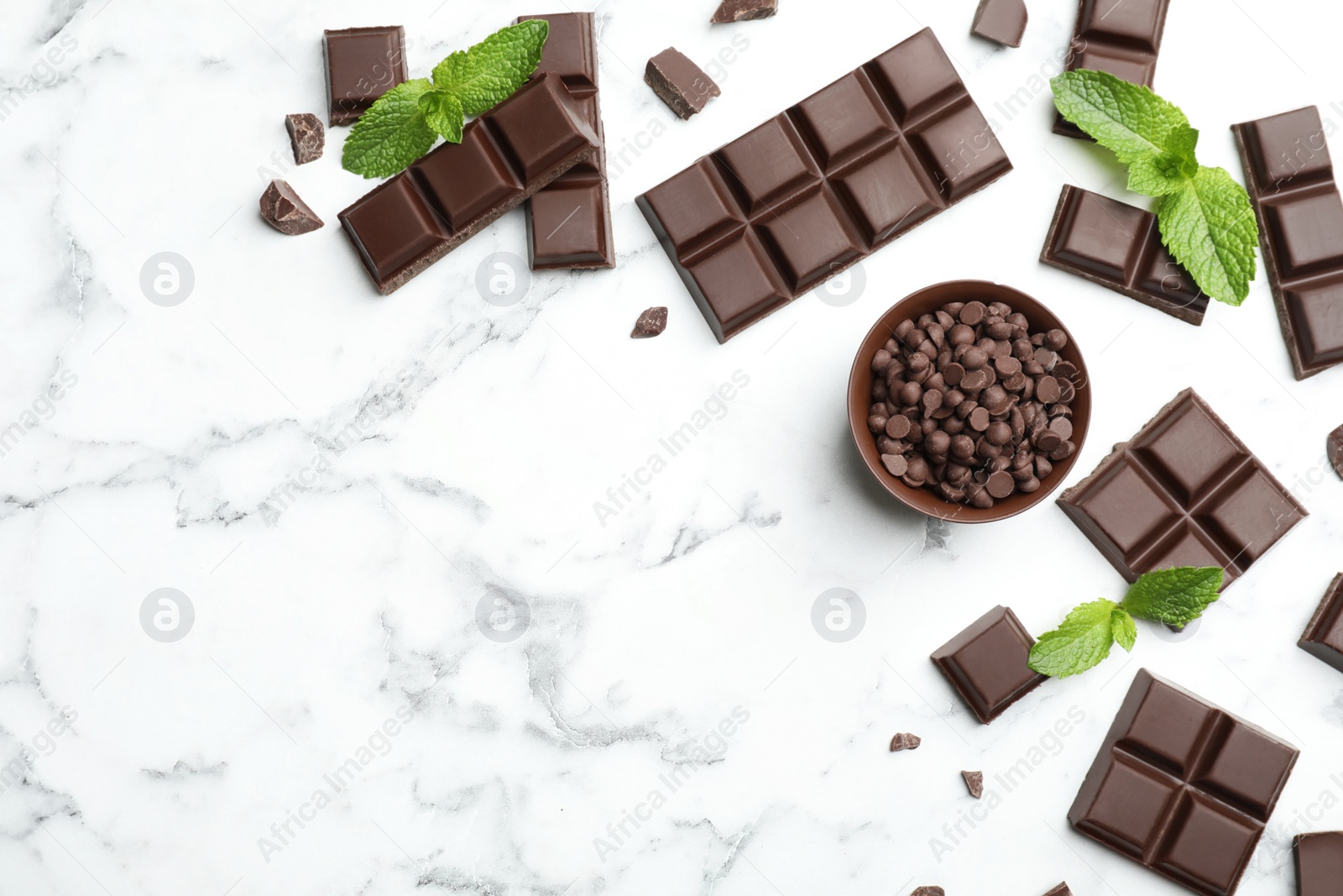 Photo of Flat lay composition with pieces of dark chocolate on marble table. Space for text