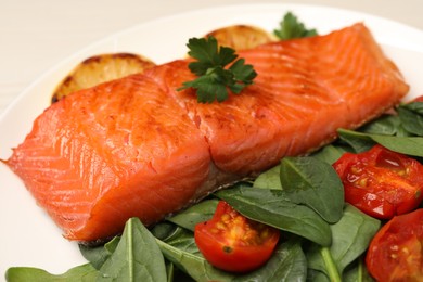 Photo of Tasty grilled salmon with basil and tomatoes on white plate, closeup