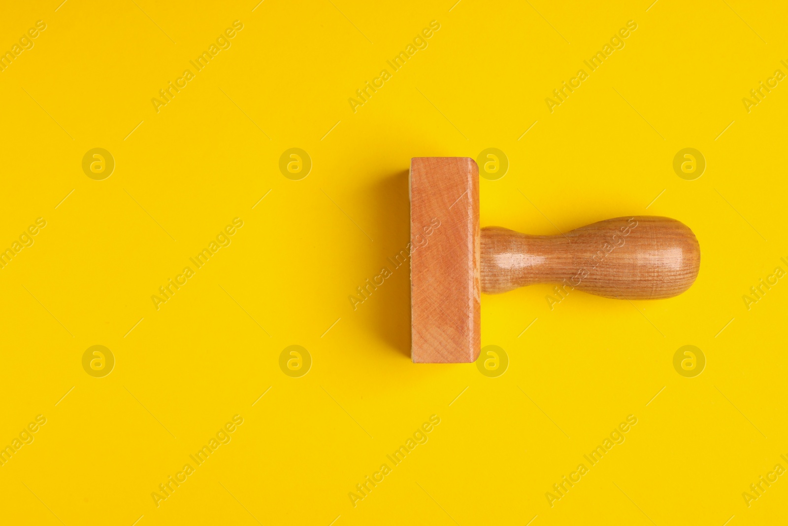 Photo of One wooden stamp tool on yellow background, top view. Space for text