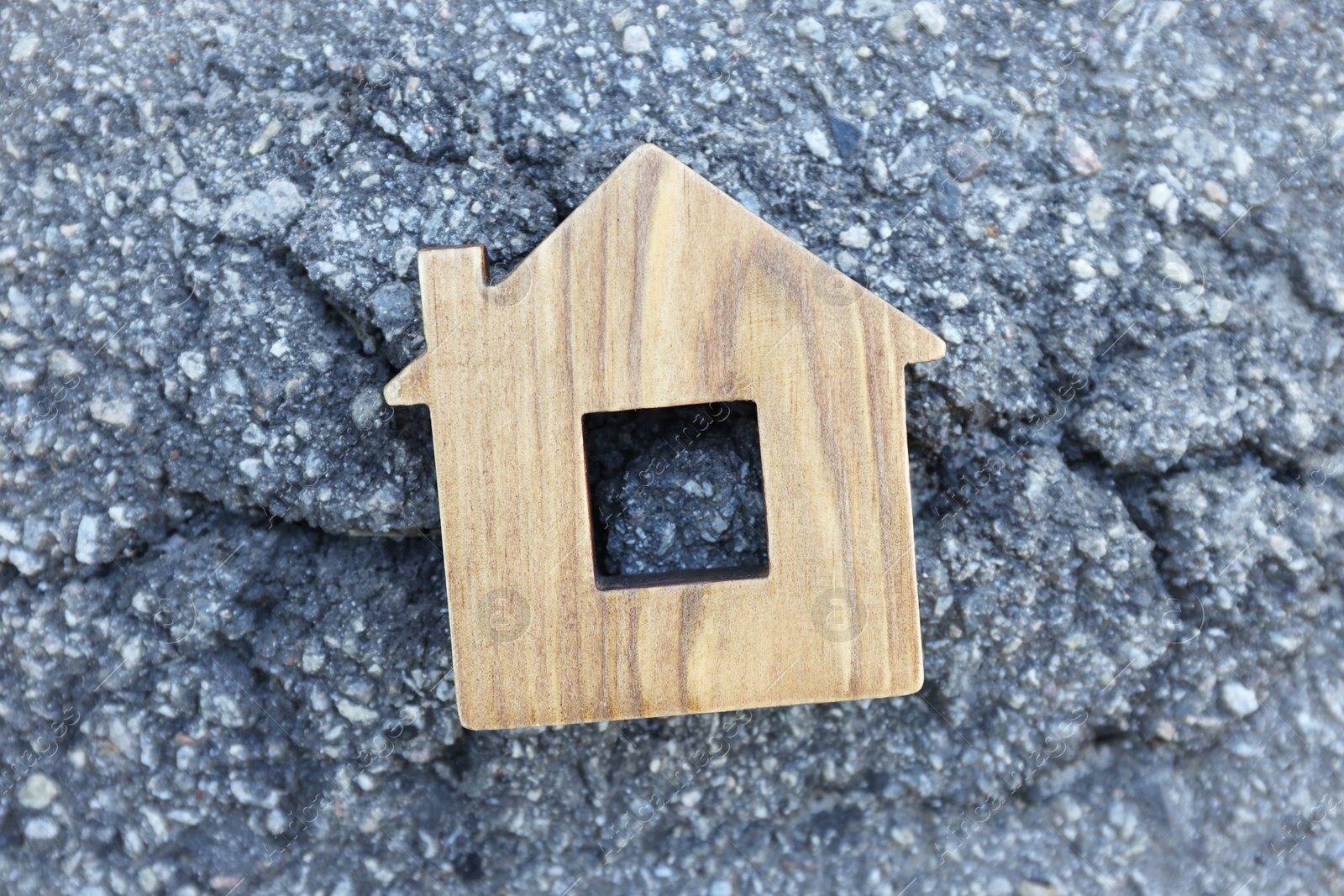 Photo of Wooden house model on cracked asphalt, top view. Earthquake disaster