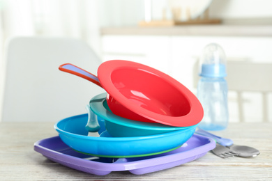 Photo of Set of plastic dishware on white wooden table indoors. Serving baby food