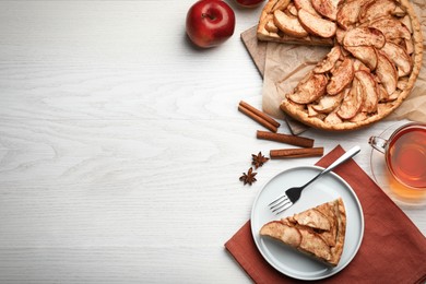 Flat lay composition with delicious apple pie, ingredients and tea on white wooden table. Space for text