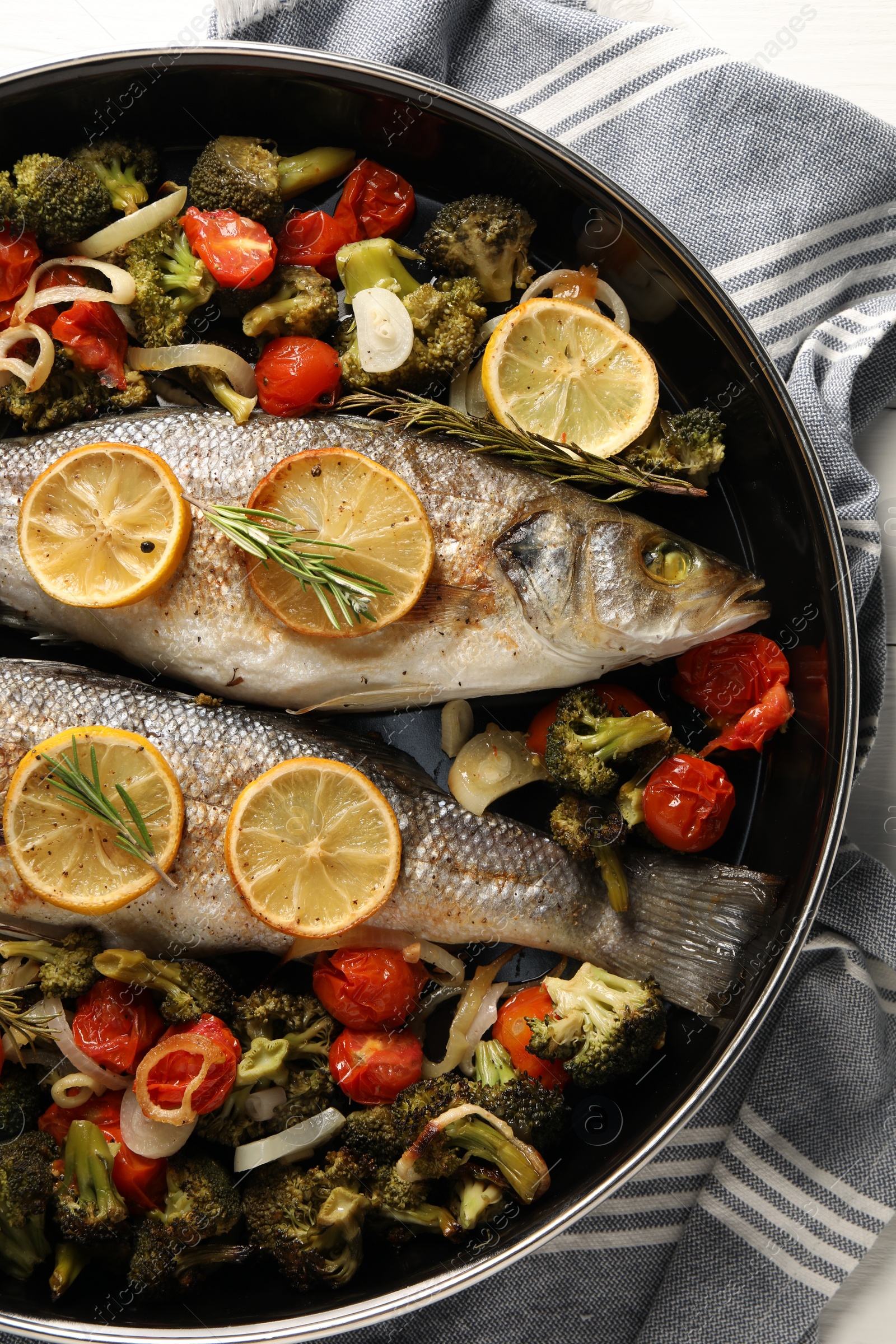 Photo of Delicious fish with vegetables, rosemary and lemon in baking dish, top view