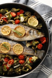 Delicious fish with vegetables, rosemary and lemon in baking dish, top view